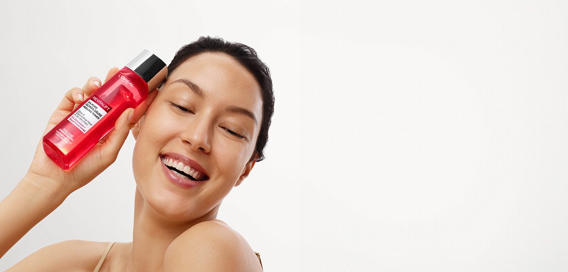 Eine Frau hält L'Oréal Revitalift Produkt neben ihr Gesicht